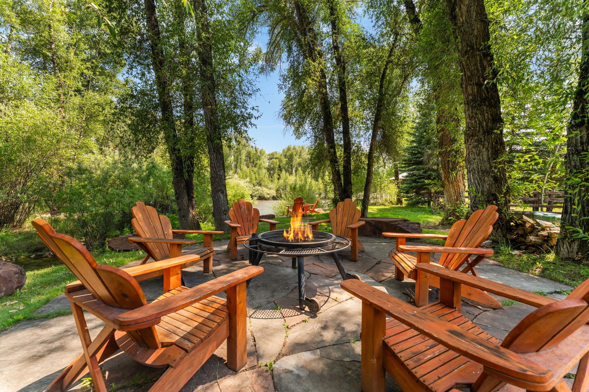 An outdoor seating area with wooden chairs and a central fire pit.