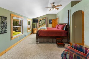 Un dormitorio con cama con dosel, ventilador de techo y vistas al exterior.