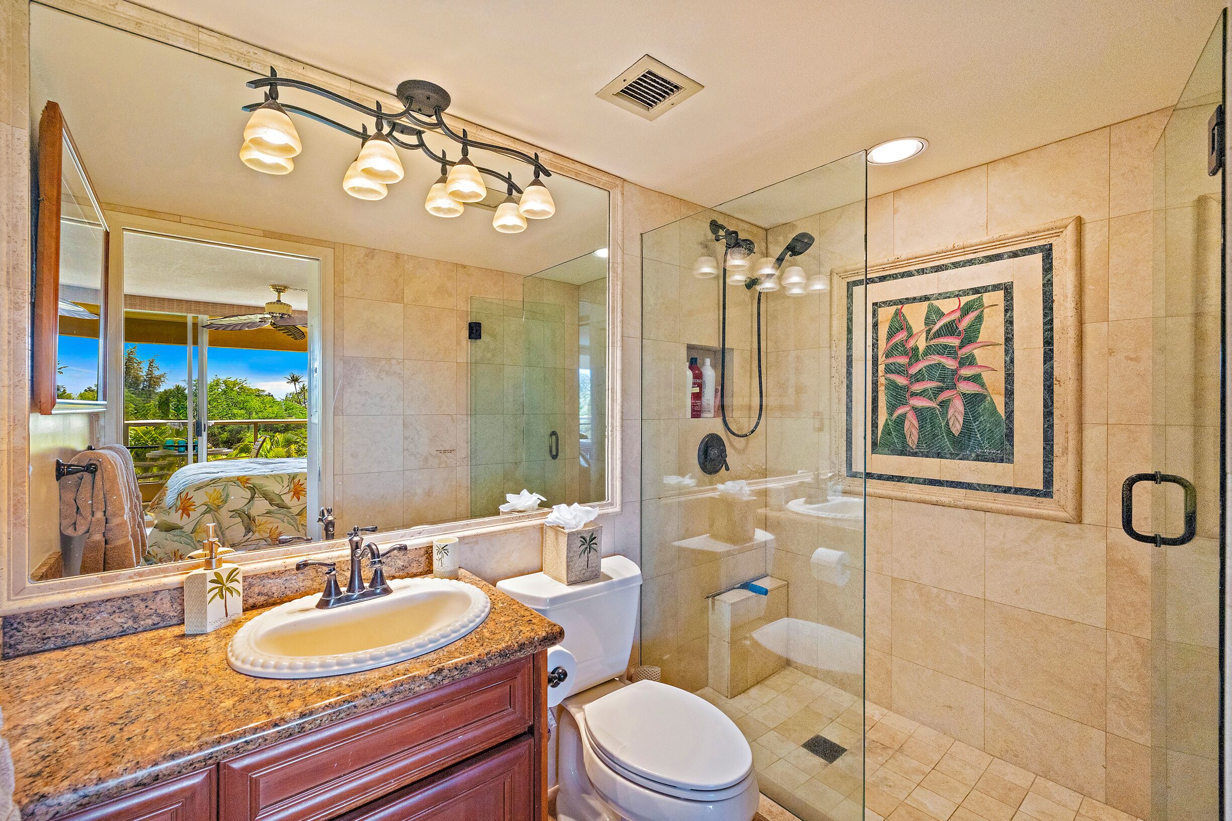 A bathroom with a granite countertop sink, a large mirror, a glass-enclosed shower, and a framed artwork on the wall.