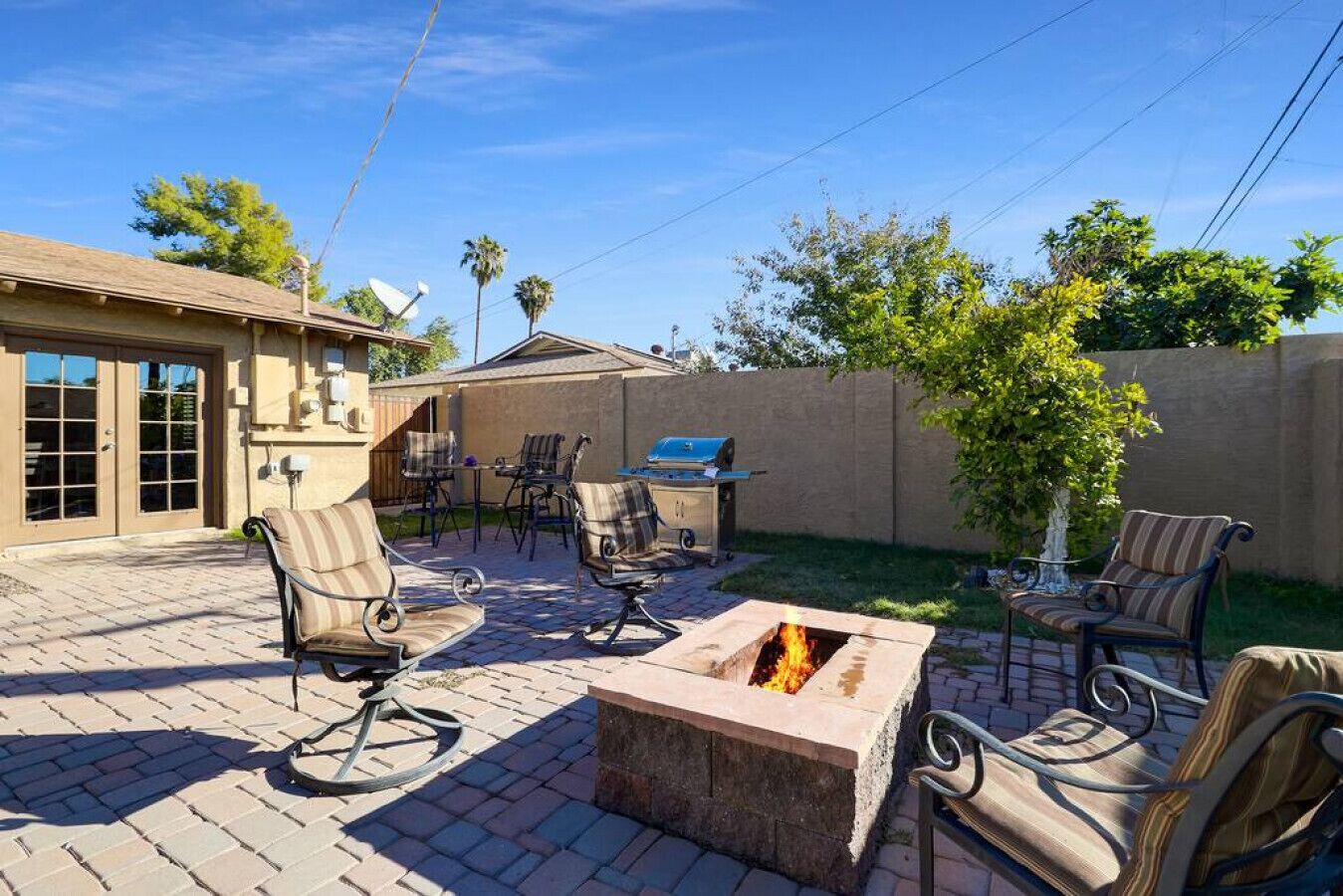 Un patio al aire libre con una chimenea, zona de estar y una parrilla.