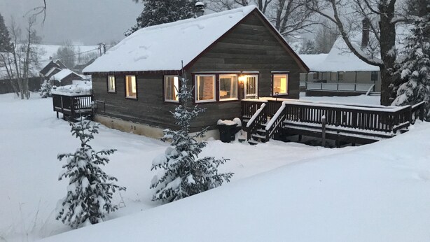 Une cabane en rondins avec une véranda, des fenêtres et une terrasse.