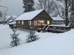 Une cabane en rondins avec une véranda, des fenêtres et une terrasse.
