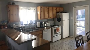 Une cuisine dotée de meubles en bois, d’une cuisinière, d’un réfrigérateur et d’un coin repas avec une table et des chaises.
