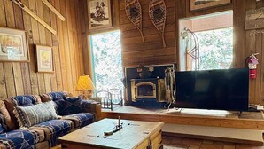 Un salon chaleureux avec un plancher en bois, un canapé, une table basse, une cheminée et un téléviseur.