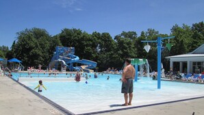 A swimming pool with a water slide and a lifeguard tower.