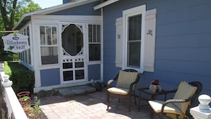 A house with a porch, two wicker chairs, and a small table.