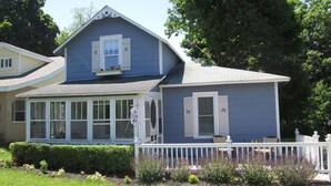 A two-story house with a covered porch and a fenced yard.