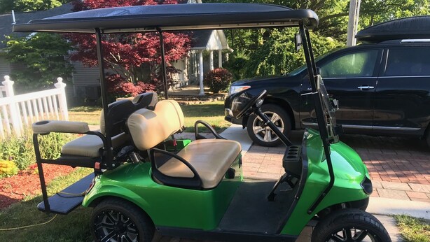 A green golf cart parked on a driveway.