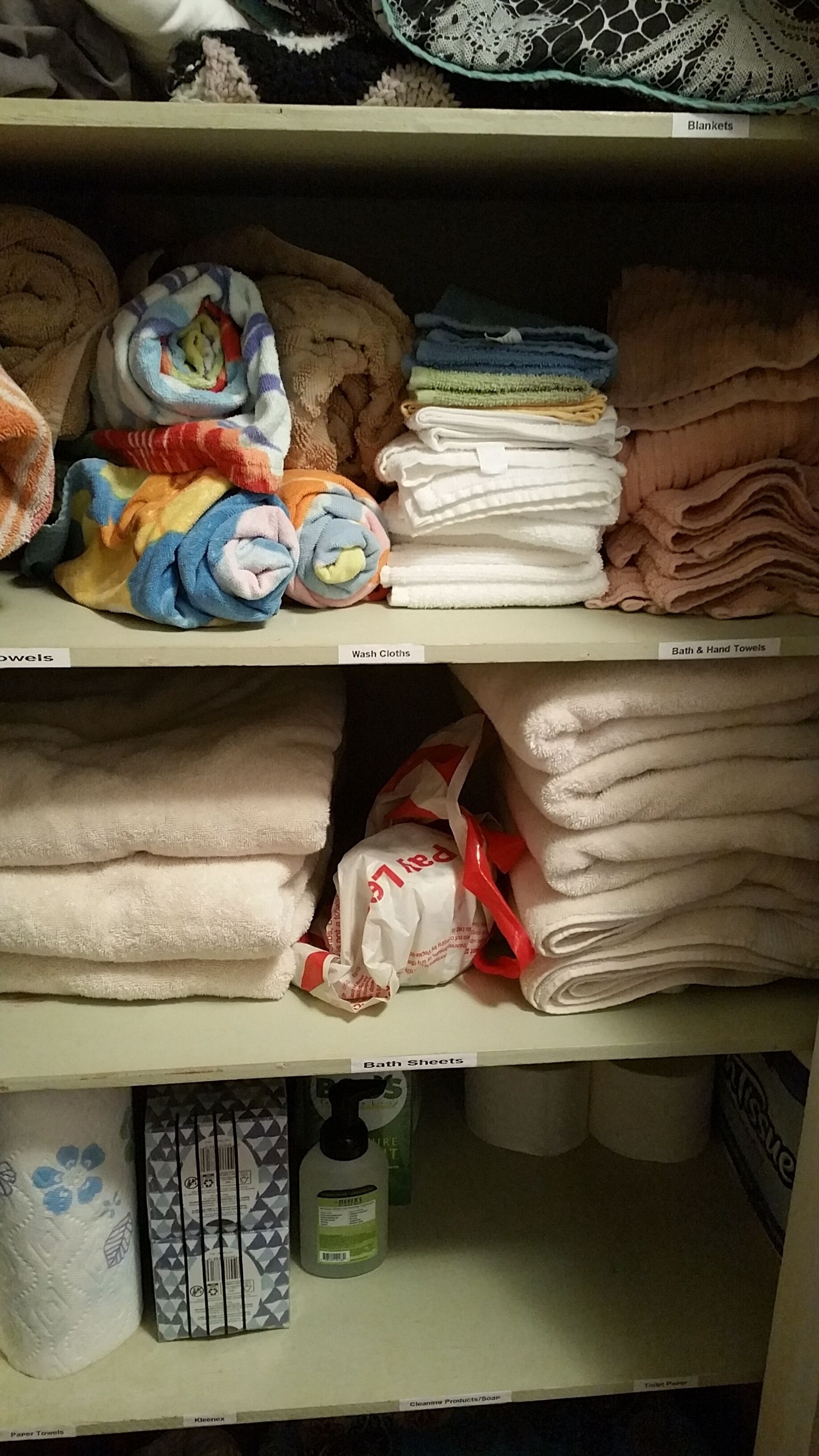 Une étagère contenant différents types de serviettes et de linge de bain, notamment des débarbouillettes, de grandes serviettes de bain et du papier toilette.
