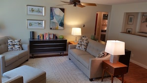A living room with a sofa, a coffee table, a bookshelf, and a lamp. - Your Home away from Home (Harbert)