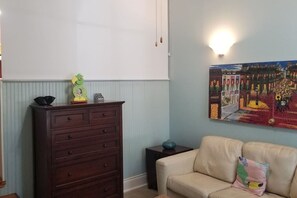 Ein Zimmer mit einem hölzernen Schminktisch, einem beigen Sofa und einem an der Wand hängenden Gemälde.