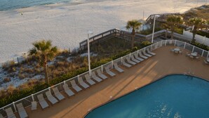 Un espace piscine avec des chaises longues et vue sur la plage.