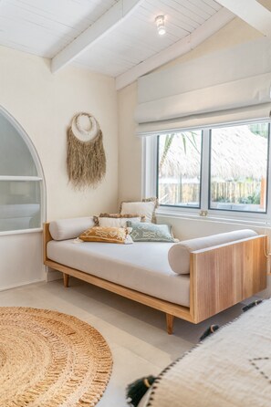Ein gemütliches Schlafzimmer mit einem Bett, einem großen Fenster und einer gewobenen Wanddekoration.