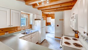 Une cuisine moderne avec des meubles blancs, un évier en acier inoxydable et une cuisinière blanche.