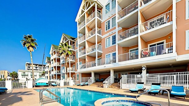 A hotel with a swimming pool, multiple balconies, and palm trees. - AMAZING BEACH VIEWS! Next to Gulf State Park (Gulf Shores)