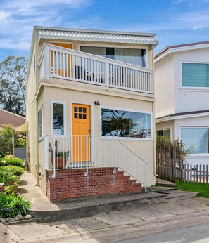 A two-story house with a balcony, a front door, and a small front yard. - Oceanfront Home with Spectacular Views on Monterey Bay.  (Pacific Grove)