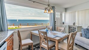 Ein Essbereich mit Meerblick, ein Holztisch mit Stühlen und eine Pendelleuchte.