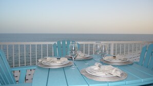 Ett bord dukat för två personer, med vita tallrikar och silverbestick, med utsikt över havet.