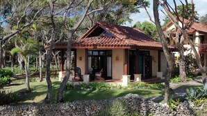 A small house with a tiled roof, surrounded by trees and a stone wall. - Sunrise Villa - An affordable beachfront gathering place for family and friends (Cabrera)