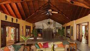 A spacious lobby with high wooden ceilings, a central seating area with sofas and a coffee table, and a ceiling fan. - Sunrise Villa - An affordable beachfront gathering place for family and friends (Cabrera)