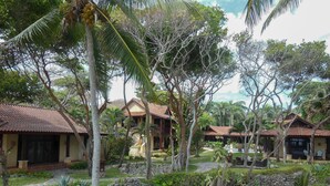 A tropical resort with multiple bungalow-style buildings, a central structure with a large staircase, and lush greenery. - Sunrise Villa - An affordable beachfront gathering place for family and friends (Cabrera)