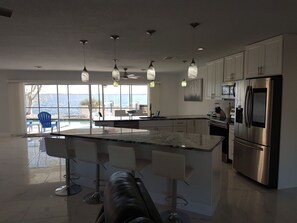 Una cocina moderna con una isla grande, electrodomésticos de acero inoxidable y vistas al mar.