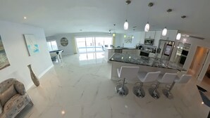 Een ruime keuken met een marmeren aanrechtblad, moderne apparatuur en hanglampen.