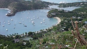 Una zona costera con numerosos veleros anclados en una bahía rodeada de exuberante vegetación y colinas.
