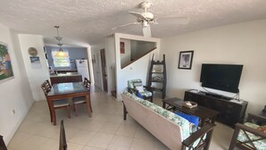 Una sala de estar con sofá, televisión y comedor.