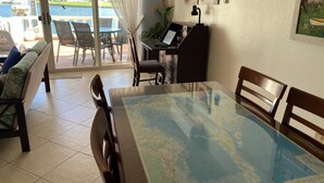Un comedor con una mesa de vidrio, sillas, un sofá y vista al agua.