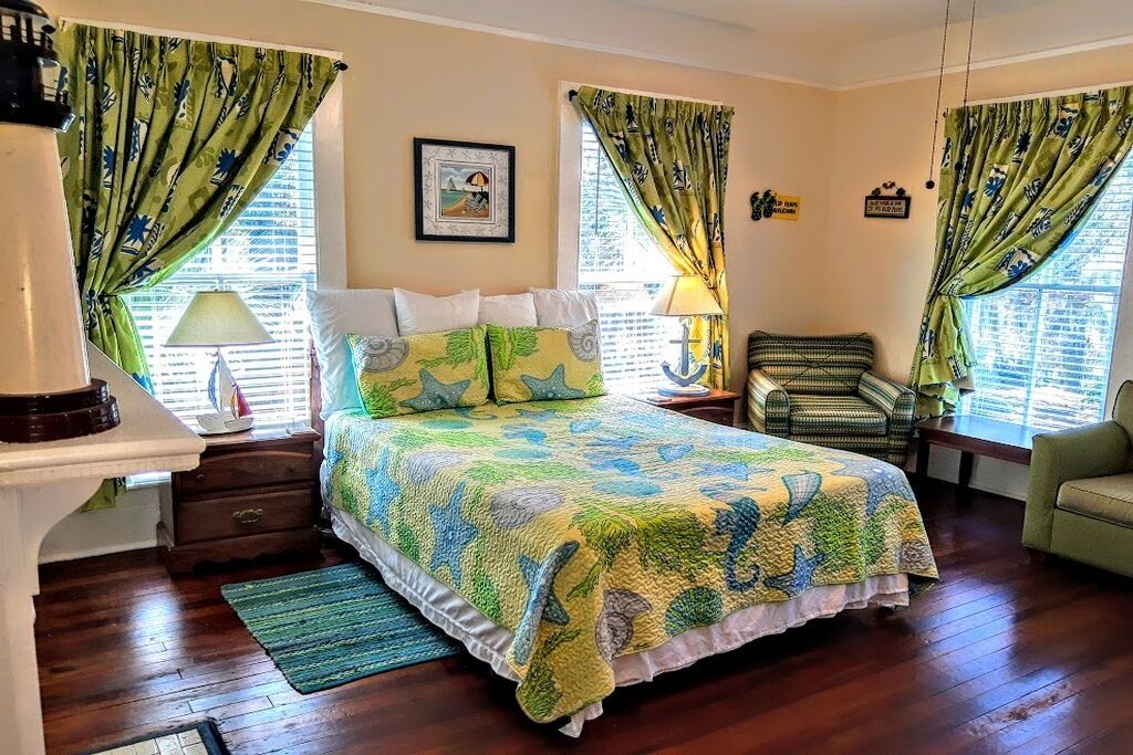 A bedroom with a bed, nightstands, a chair, and curtains.