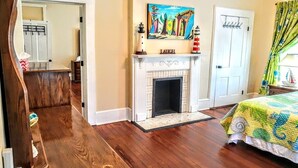 A bedroom with a fireplace, a bed with a colorful quilt, and a painting above the fireplace. - 2brCoastalColonialApt between Jekyll & St Simons Islands beaches& near Downtown! (Brunswick)