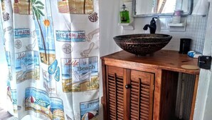 A bathroom with a wooden vanity, a large bowl sink, a black faucet, and a beach-themed shower curtain. - 2brCoastalColonialApt between Jekyll & St Simons Islands beaches& near Downtown! (Brunswick)