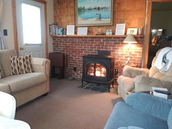 A cozy living room with a brick fireplace, a sofa, a chair, and a bookshelf. - Music makers' cottage (Grand Marais)