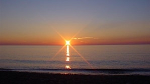 Un atardecer sobre un mar tranquilo con un horizonte despejado.