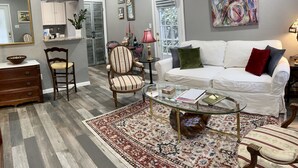 A living room with a white sofa, a glass coffee table, a patterned rug, and a wooden chair.