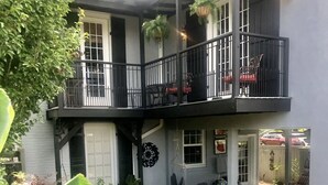 A two-story house with a balcony, outdoor seating area, and a garden.