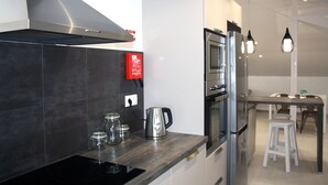 A modern kitchen with a built-in oven, a stainless steel range hood, and a coffee maker on the counter. - Fantastic - Cabo Girão view  (Câmara de Lobos)