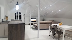 A modern loft-style room with a kitchen area, a dining table with chairs, a sofa, and a television. - Fantastic - Cabo Girão view  (Câmara de Lobos)
