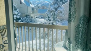 Un balcón con vistas a árboles nevados y una casa.