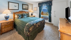 A bedroom with a bed, two nightstands, a dresser, a television, and a window with curtains. - Columbine 2107 (Crested Butte)