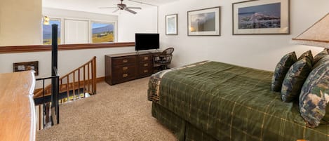Quarto com cama, penteadeira, televisão e ventoinha no teto.