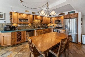Une cuisine avec des meubles de rangement en bois, un réfrigérateur en acier inoxydable et une table à manger avec des chaises.