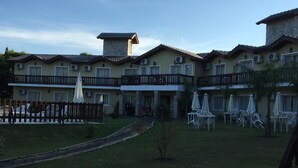 A hotel with multiple balconies, outdoor seating, and a well-maintained lawn.