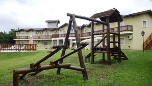 A playground with wooden structures and a building with balconies in the background.
