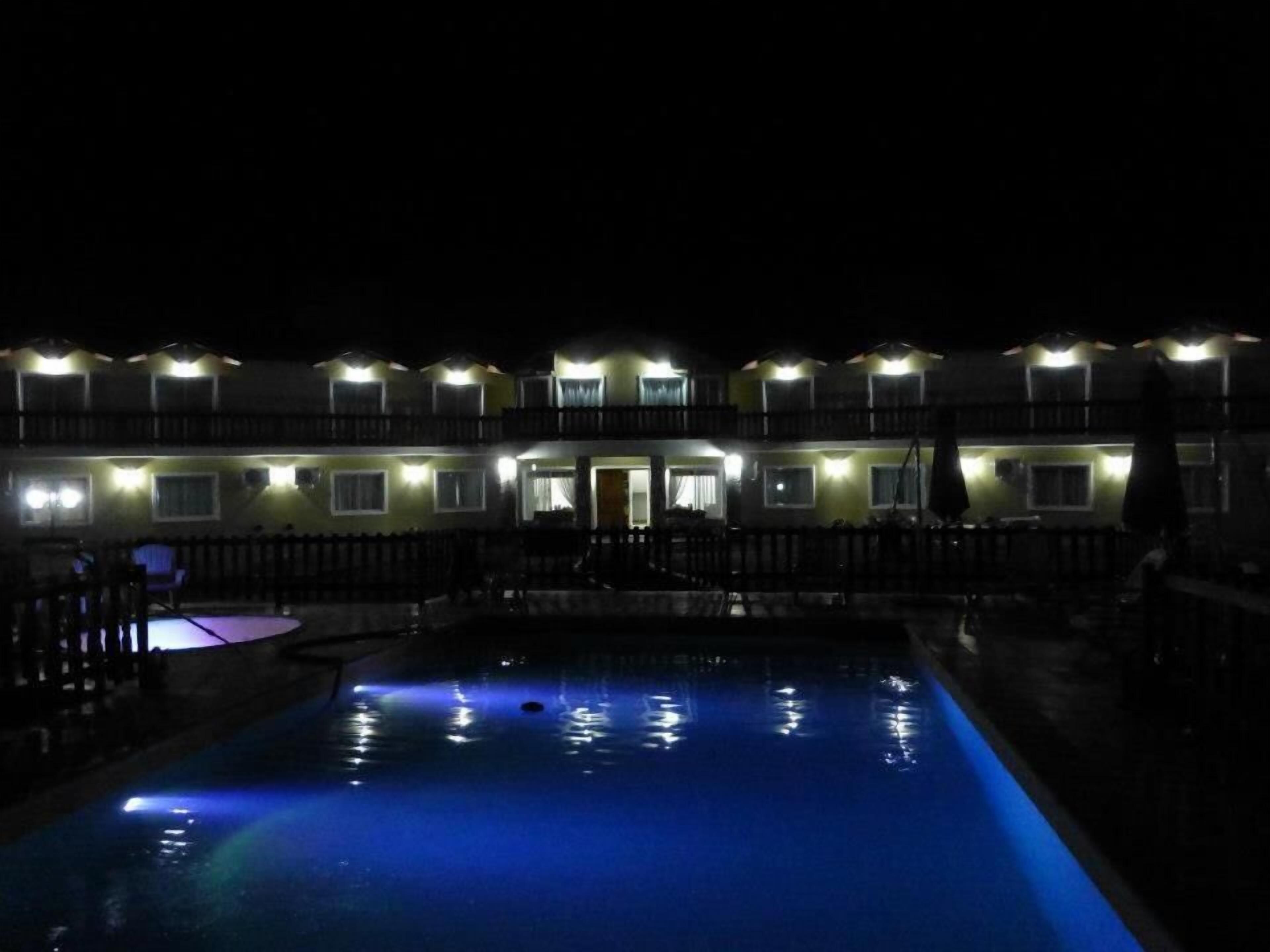 Un hotel con piscina iluminado por luces colgantes en la noche.