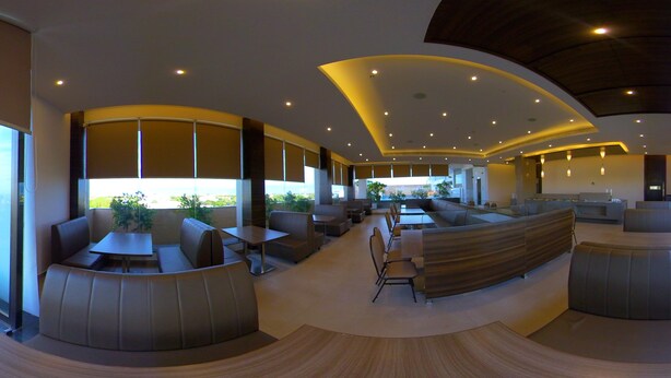 A modern interior with a curved ceiling, seating areas, and large windows offering a view of the city. - Hotel Blossoms (Tiruchirappalli)