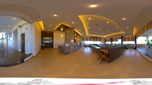 A spacious hotel lobby with a modern design, featuring a central seating area, a reception desk, and a large window providing natural light. - Hotel Blossoms (Tiruchirappalli)