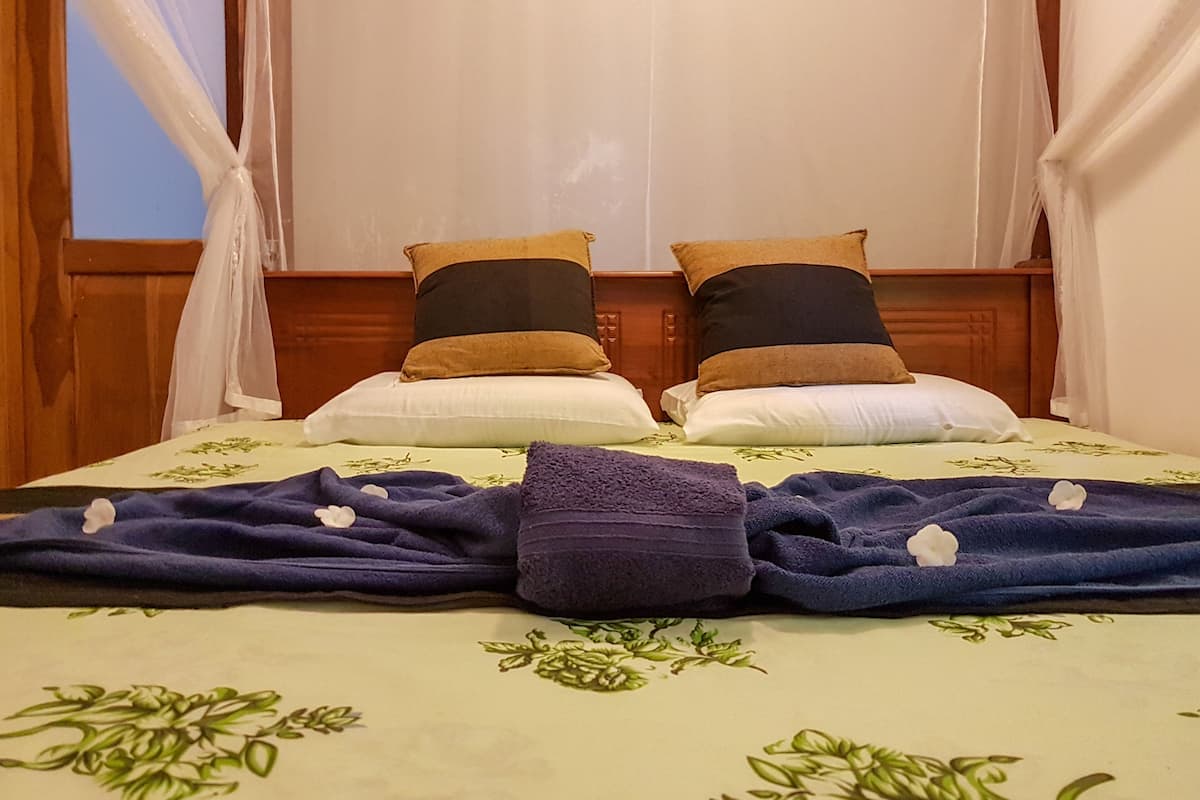 A bed with a floral bedspread, two pillows, and a folded towel.
