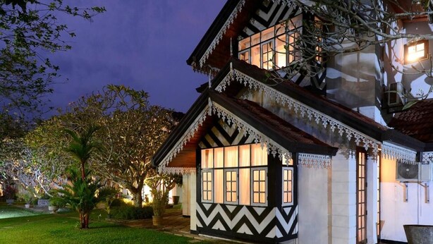 Een traditioneel huis met een ontwerp van twee verdiepingen, met een opvallend raam met veel ruitjes en decoratieve witte sierlijsten.